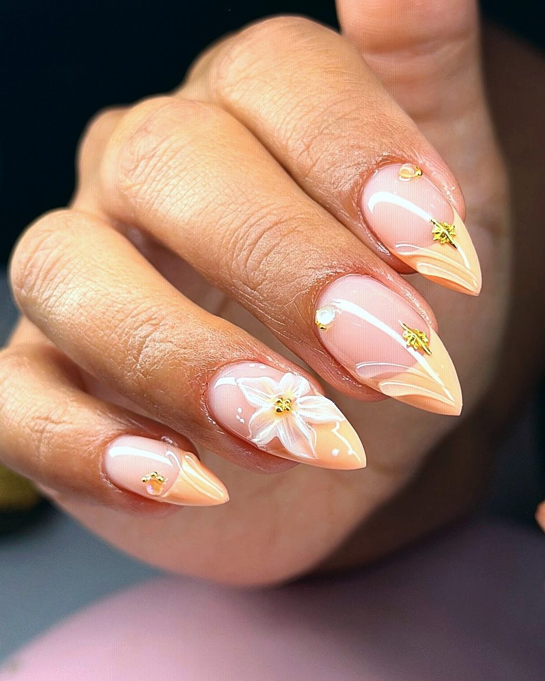 Uñas almendradas color durazno con una flor pintada a mano